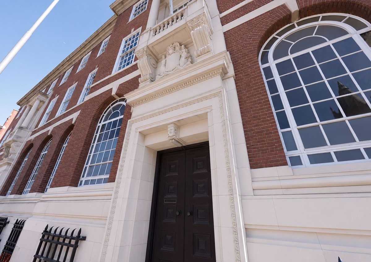Looking up at the Portland stone entrance and arched windows of the red-brick Priors Gate façade